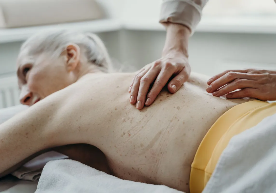 Seniorin genießt eine sanfte Rückenmassage.